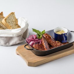 Smoked sausages roasted with dark beer and vegetables, served with tarragon mustard and bread from our oven